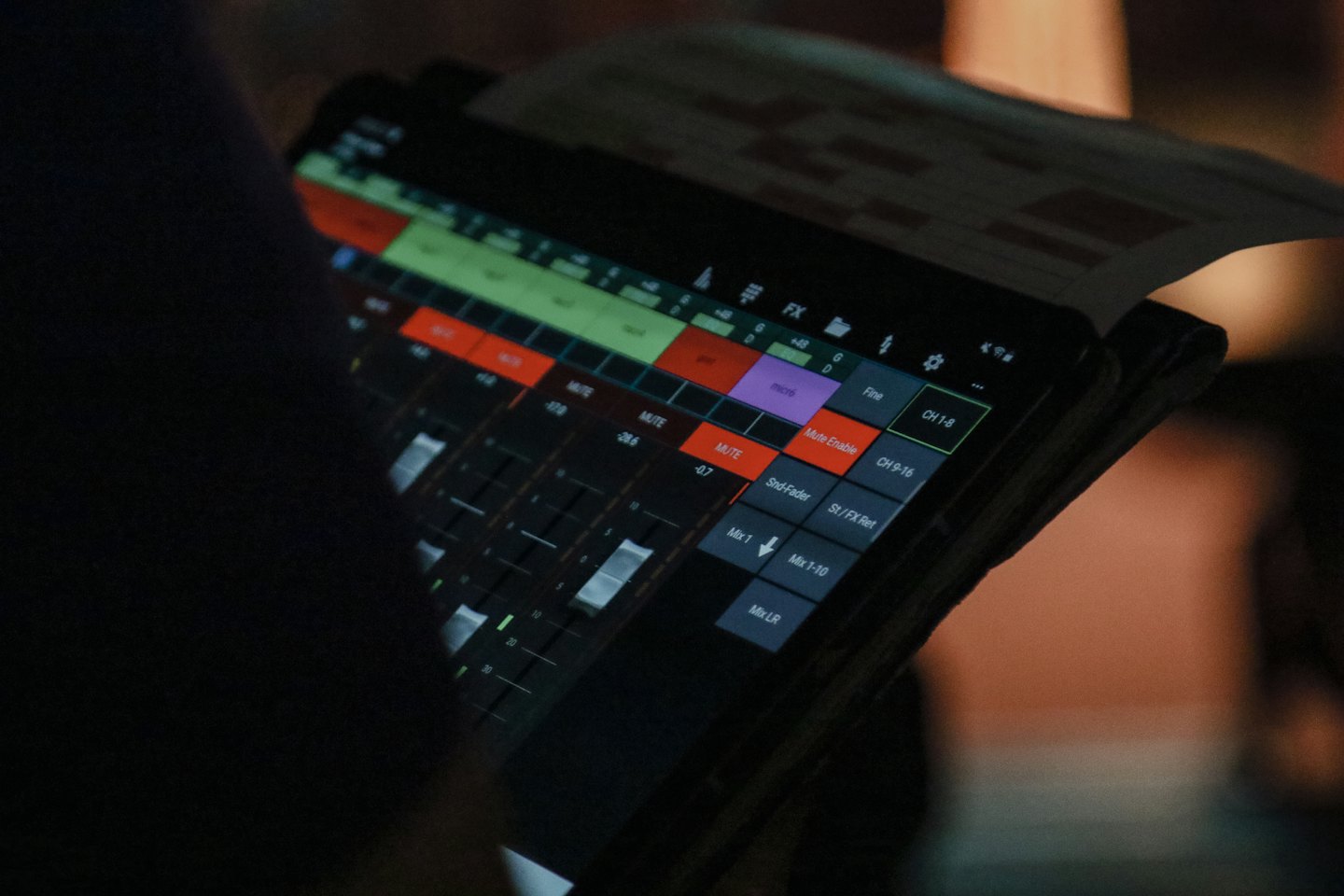 Person uses a tablet with audio mixing software.